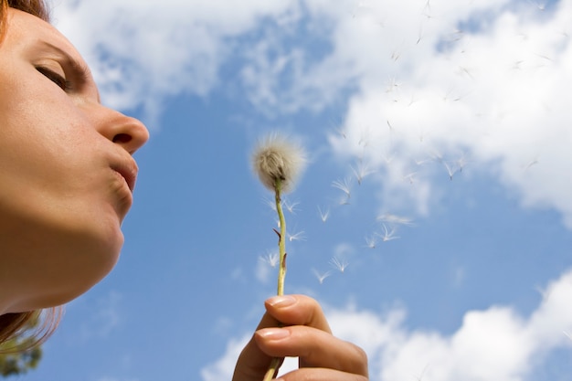 Foto la donna esprime un desiderio mentre soffia un fiore