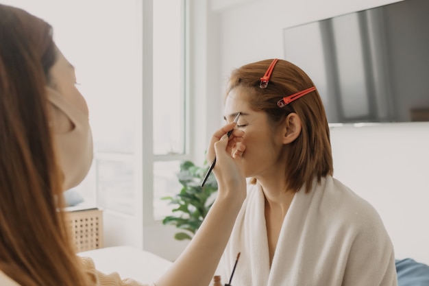 Woman makeup artist is at work and wearing makeup on her model