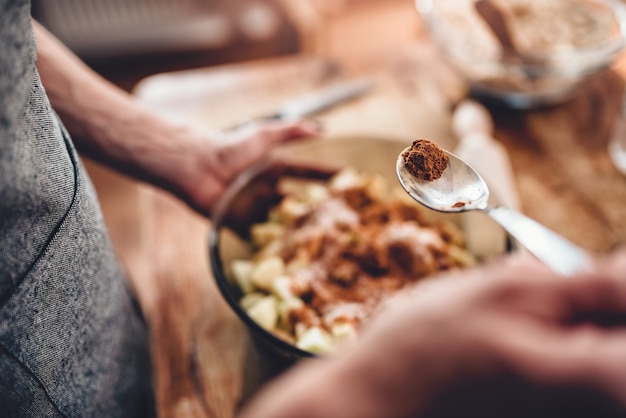 Woman making apple pie and adding spice