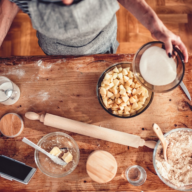 Woman making apple pie on wooden table