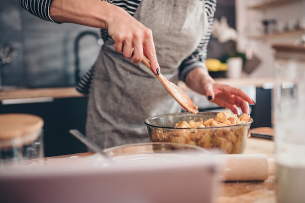 Woman making apple pie on wooden table