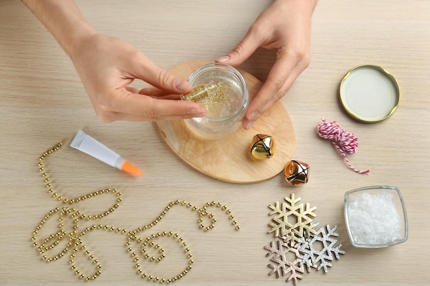 Woman making beautiful snow globe at wooden table top view