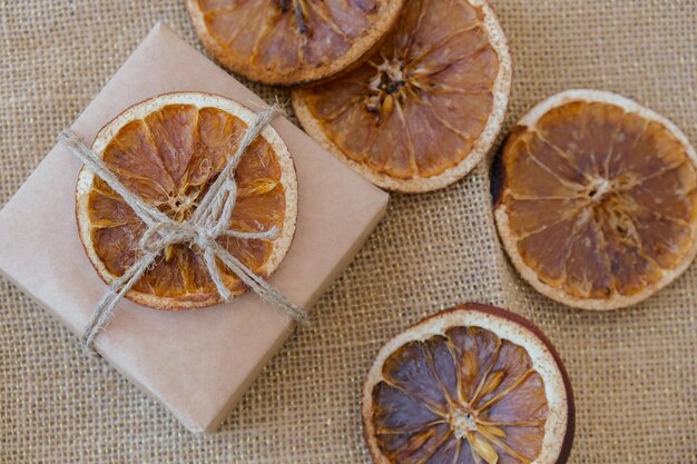 Woman making box with new year\'s gifts wrapped in craft paper\
and decorated with dry orange slices holidays and gifts concept\
handmade eco friendly alternative green christmas presents zero\
waste