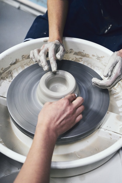 Woman making ceramic pottery, four hands close-up, focus on potters, palms with pottery