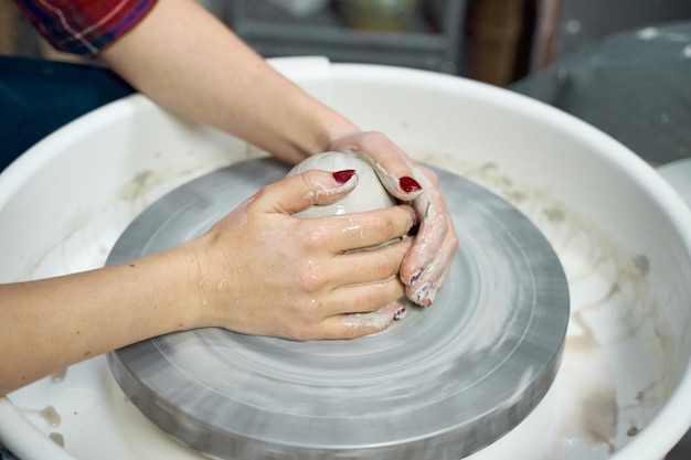 Woman making ceramic pottery on wheel, hands closeup. Concept for woman in freelance