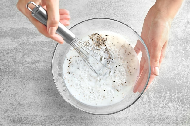 Woman making chia seed pudding on kitchen table