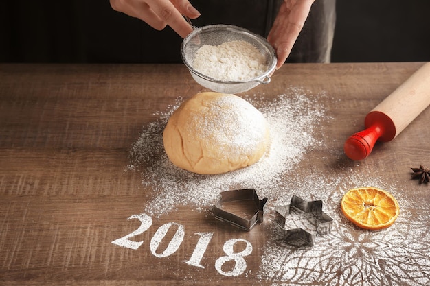 クリスマスのクッキーを作る女性と木製のテーブルに小麦粉で作られた2018