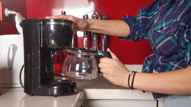 コーヒーメーカーのマシンでコーヒーを作る女性