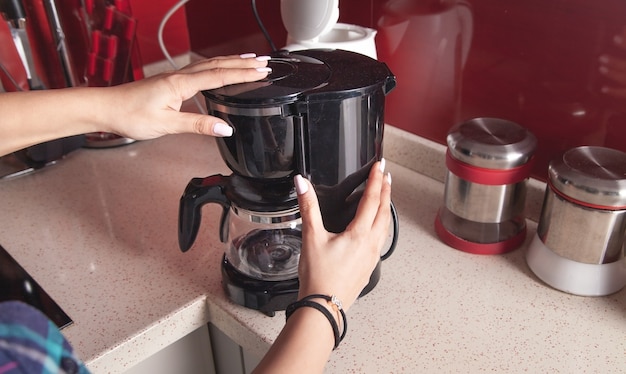 Woman making coffee in a coffee maker machine.