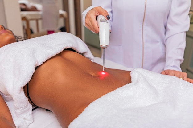 Photo woman making continuous and direct application of therapeutic laser on the radial artery in the belly in the spa woman undergoing aesthetic treatment with ilib