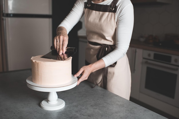 キッチンのクローズアップでクリーミーなバースデーケーキを作る女性休日の時間選択的な焦点