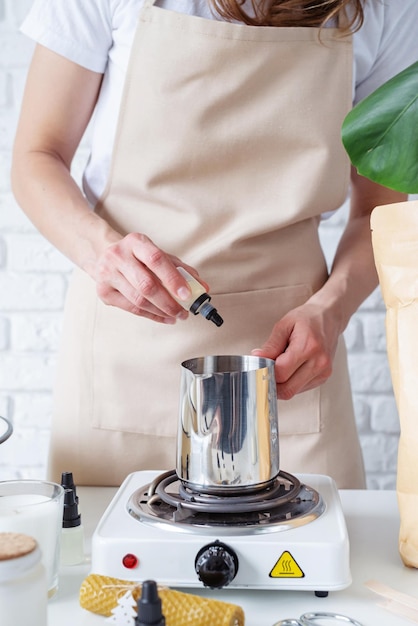 Woman making decorative aroma candle adding aroma closeup