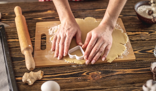 Woman making delicious homemade cookies in the shape of heart in her kitchen
