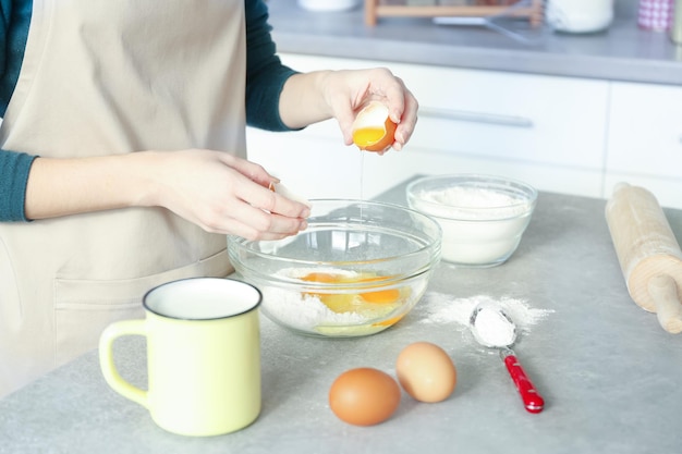 Woman making dough in glass bowl at kitchen