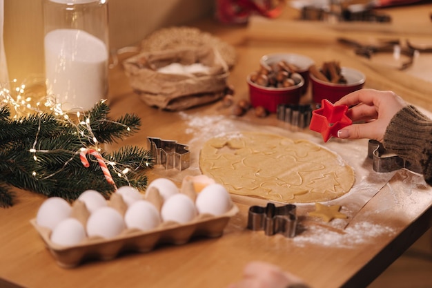 Woman making gingerbread at home female cutting cookies of gingerbread dough view from above top