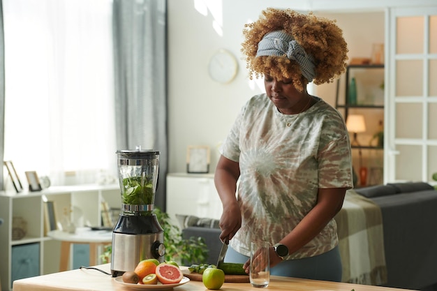 Woman making green smoothie at home