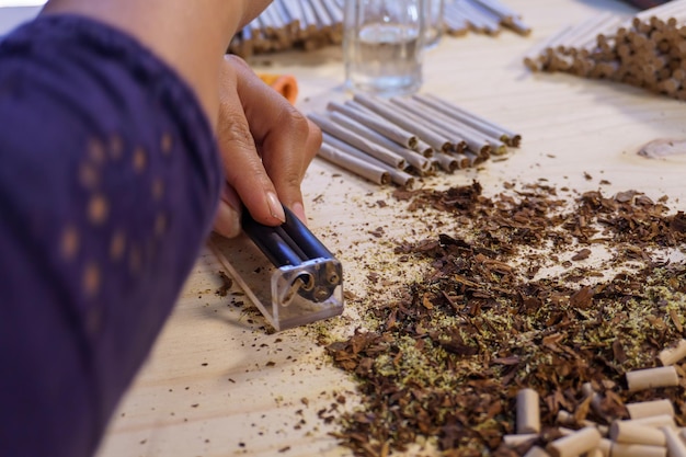 Woman making hand-wrapped cigarettes on a table