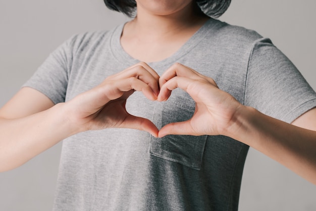 Donna che fa le mani a forma di cuore, donazione, volontario di beneficenza felice, concetto di giornata mondiale del cuore