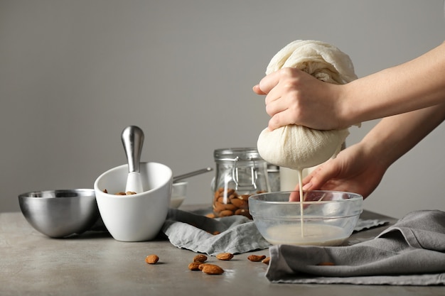 Woman making healthy almond milk in kitchen