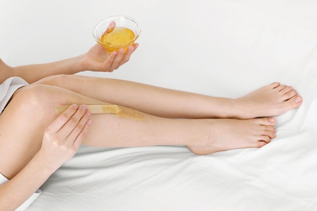 Photo woman making legs depilation sitting on bed