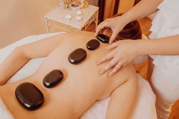 Woman making massages by lava stones in a beauty saloon lifestyle and healthcare concept