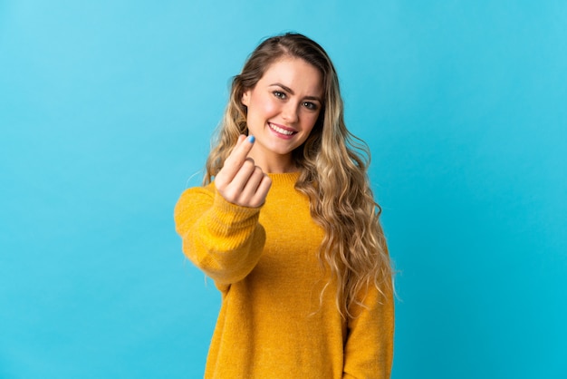 Woman making money gesture isolated on blue