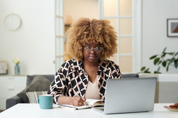 Woman making notes during online conference