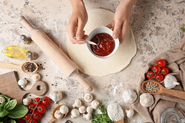 Woman making pizza on light surface