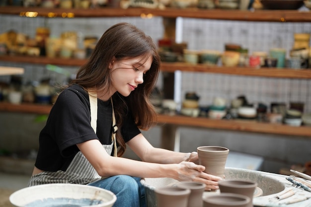 Woman making pottery in workshop Shaping wet clay on pottery wheel