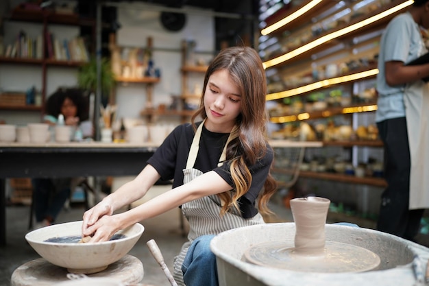 Woman making pottery in workshop Shaping wet clay on pottery wheel