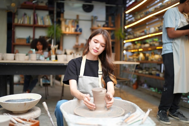 Donna che fa la ceramica in officina modellatura dell'argilla bagnata sul tornio delle ceramiche