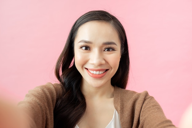 Woman making selfie. pink background