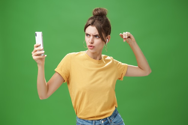 Woman making serious look to take selfie while listening music in wireless earphones