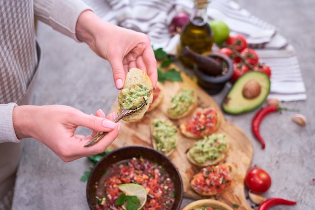 Photo woman making tasty salsa and guacamole bruschetta snacks at domestic kitchen