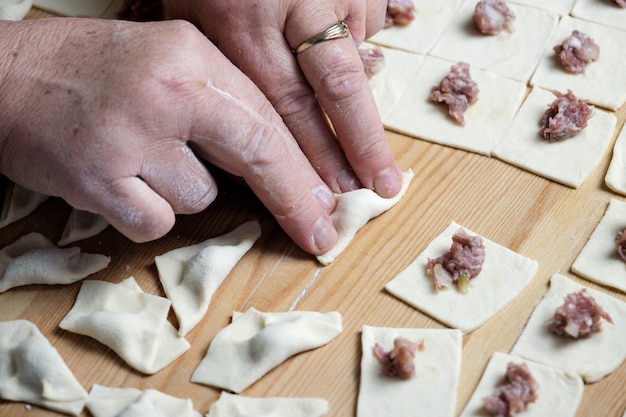 Foto una donna che fa i ravioli turchi su un tavolo di legno.