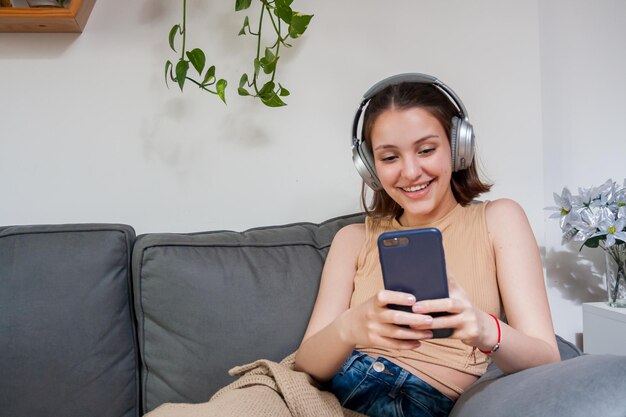 Woman making a video call on her cell phone using\
headphones