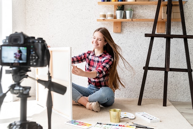 Woman making a video for her blog on art using a tripod mounted digital camera