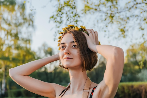 woman making wreath of flowers dandelions on flowering field Summer lifestyle