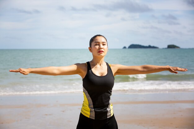 朝のビーチでヨガの練習をする若い女性。