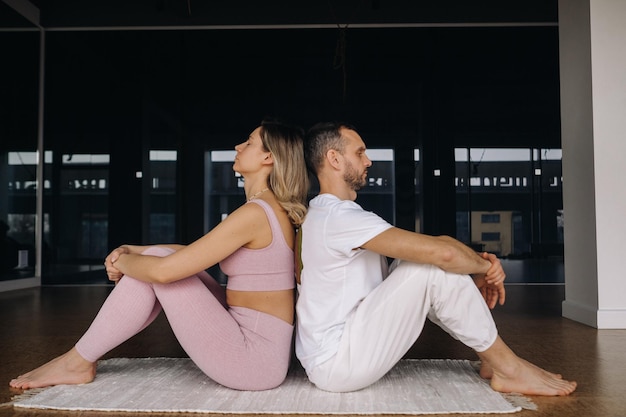 A woman and a man are engaged in pair gymnastics yoga in the gym