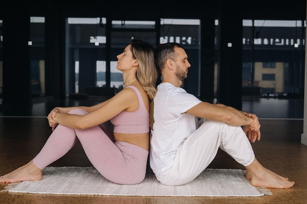 Una donna e un uomo sono impegnati in ginnastica yoga in coppia in palestra