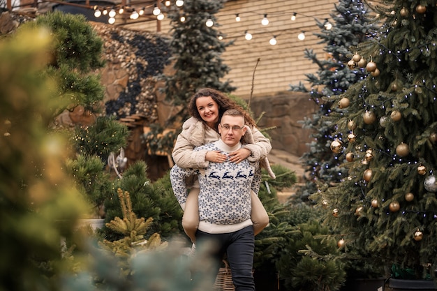 A woman and a man are standing near the Christmas tree, they are happy, new year's mood