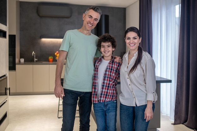 Donna uomo e ragazzo sorridente alla macchina fotografica a casa