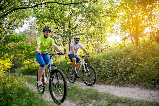 a woman and a man cycling in summer in the park on bicycles