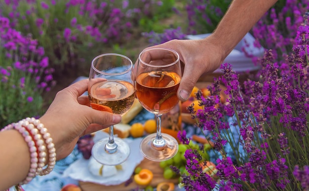 Una donna e un uomo bevono vino in un campo di lavanda messa a fuoco selettiva