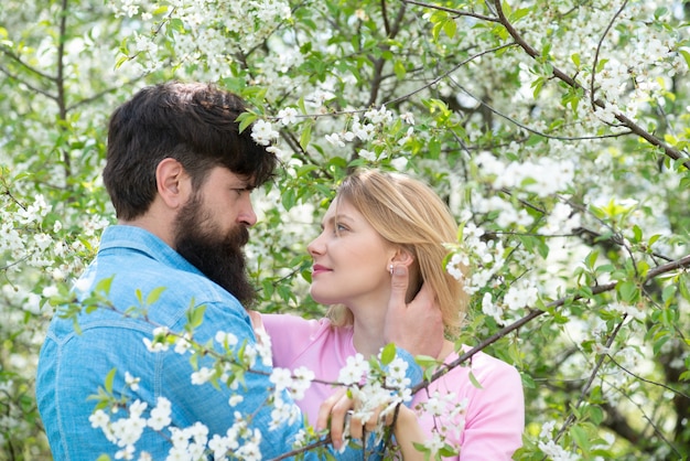 Foto donna e uomo che godono di relazioni perfette e trascorrono vacanze primaverili. giovani coppie felici vicino all'albero del fiore.