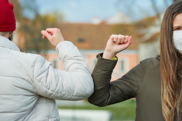 A woman and a man in face masks bump elbows instead of greeting with a handshake