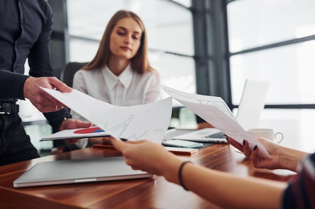 Woman and man in formal clothes working together indoors in the office by table with documents.