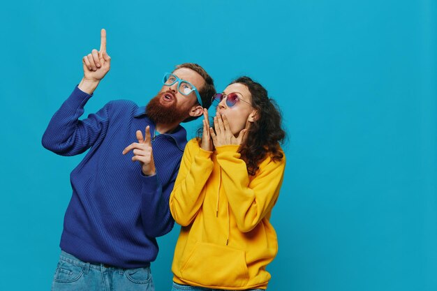 Foto una donna e un uomo si divertono a girare e mostrare segni con le mani che sorridono allegramente su uno sfondo blu il concetto di una vera relazione in una famiglia