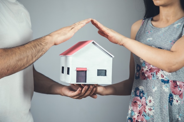 Modello di casa mano uomo e donna su grigio